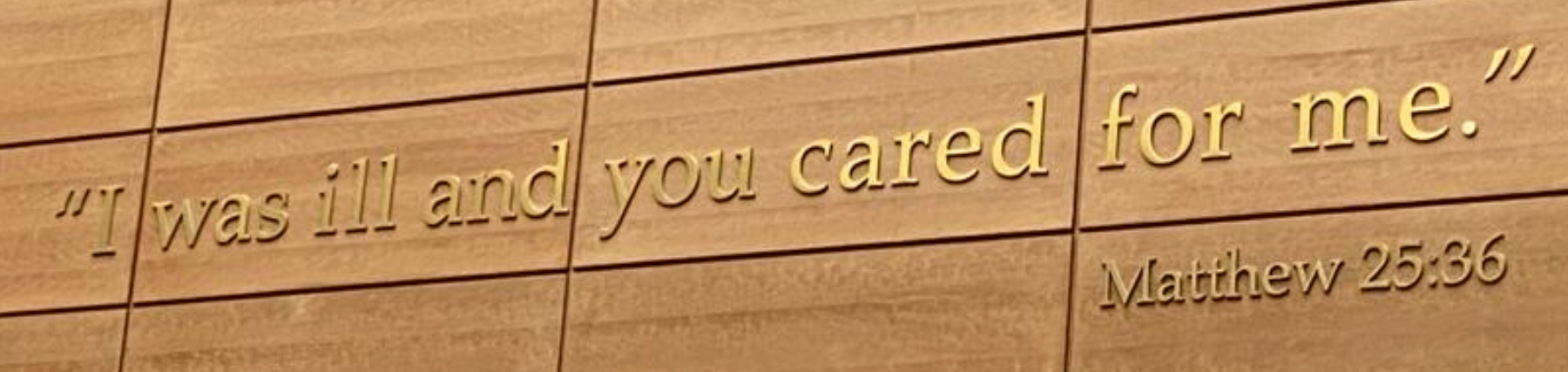 Image of a wall quote on Loyola University Chicago’s campus reading, ‘I was ill and you cared for me. - Matthew 25:36.’